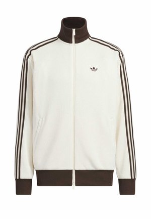 White zip-up track jacket with brown ribbed collar, cuffs, and hem, featuring three brown stripes down sleeves and small logo on chest.