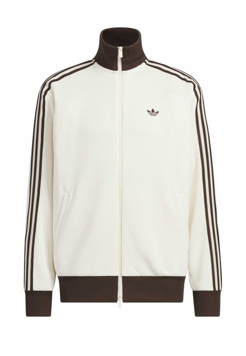 Witte sportjas met rits en een bruine geribde kraag, manchetten en zoom, met drie bruine strepen op de mouwen en een klein logo op de borst.