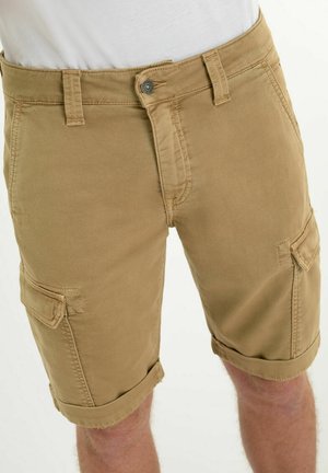 Pantaloncini cargo beige da uomo con chiusura con bottone e cerniera, passanti per cintura e tasche con patta ai lati, indossati con una camicia bianca.