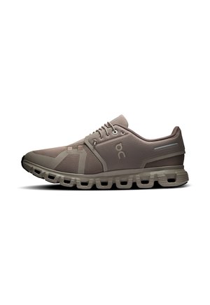 Taupefarbener Sportschuh mit Mesh-Obermaterial, Schnürsenkeln und markant segmentiertem Sohlen-Design, von der Außenseite vor weißem Hintergrund gezeigt.