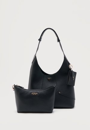 Sac à main Guess en cuir noir avec bandoulière réglable, petite pochette zippée et porte-clés attaché sur fond blanc uni.