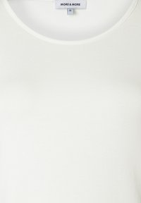 Weißes kurzärmeliges Oberteil mit rundem Halsausschnitt, aus weichem, dehnbarem Stoff. Etikett zeigt "MORE & MORE", Größe 36. Glatte Textur, minimalistisches Design.