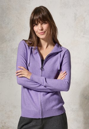 Sweater zippé violet clair avec une capuche et des poignets côtelés. Présente des rayures horizontales et un cordon de serrage au niveau du cou.