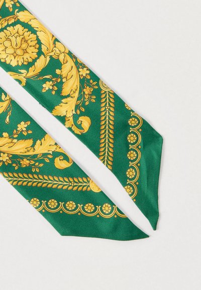 Πράσινη μεταξωτή γραβάτα με περίπλοκα κίτρινα λουλουδένια και φυλλώδη σχέδια, διακοσμητικά στοιχεία και λεία υφή. Ολοκληρώνεται με κλασικό μυτερό σχήμα.
