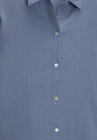 Ljusblå button-up skjorta gjord av texturerat tyg med horisontella linjer, med en krage och fem vita knappar fram.