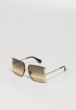 Gafas de sol con un marco cuadrado metálico con acentos dorados y lentes marrones degradados. Patillas negras con un acabado brillante.