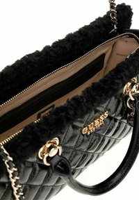 Sac à main noir matelassé avec garniture en fausse fourrure, accents en métal doré et intérieur beige. Il comporte une poche zippée et une bandoulière en chaîne.