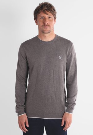 Pull marron à manches longues avec encolure et poignets côtelés. Détail de logo subtil sur la poitrine. Texture de tissu lisse, coupe régulière.