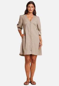 Beige linjekjole med V-hals, knapp foran, puffermer og sidelommer, med avslappet passform og glatt tekstur.