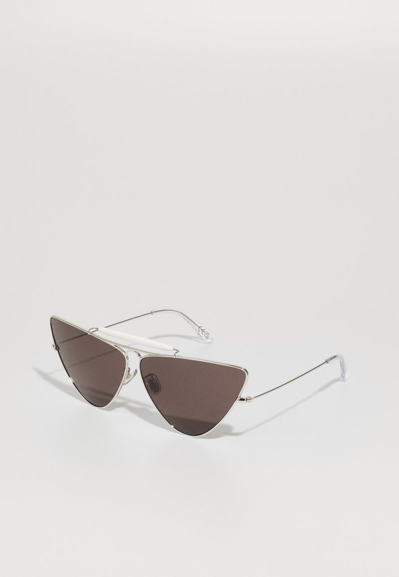 Ochelari de soare tip cat-eye cu cadrul din metal argintiu, lentile de culoare maro închis și accente din plastic alb pe brațe.