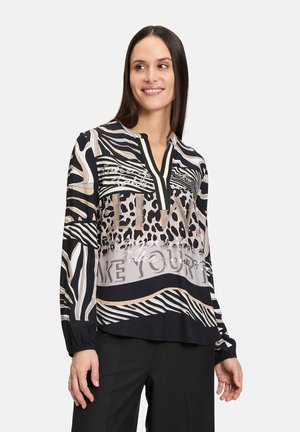 Langarmbluse in Schwarz, Beige und Creme mit Tier- und abstrakten Mustern. Mit einem Knopfleisten-Ausschnitt und elastischen Manschetten. Weiches, fließendes Material.
