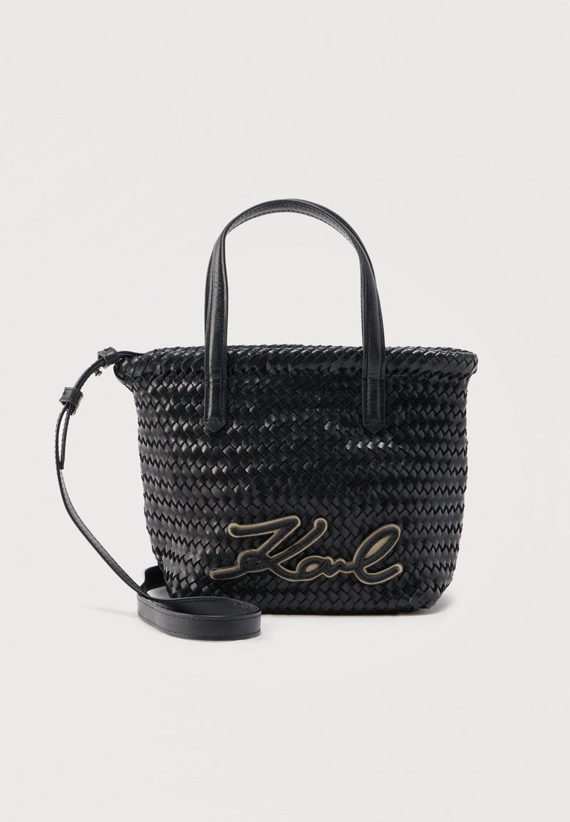 Μαύρη πλεκτή δερμάτινη τσάντα χειρός με δύο επάνω λαβές, ρυθμιζόμενο λουρί ώμου και κεντημένο το όνομα "Karl" στο μπροστινό μέρος.