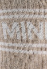 Dzianina w beżowo-białe paski z dużym białym napisem "MINI", charakteryzującą się miękką fakturą i równym wzorem.