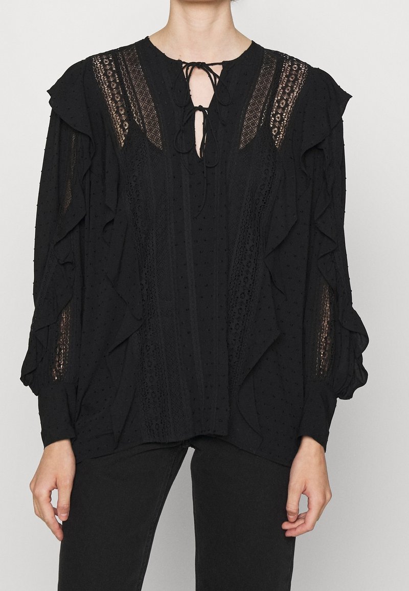 Blusa nera con volant, maniche lunghe, realizzata in tessuto texturizzato, con pannelli in pizzo trasparente e dettaglio alla scollatura con la possibilità di fare un nodo.