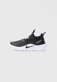 Baskets de sport noires avec une tige texturée, une sangle élastique et une semelle blanche. Présente le logo "JUST DO IT" et un design épuré.
