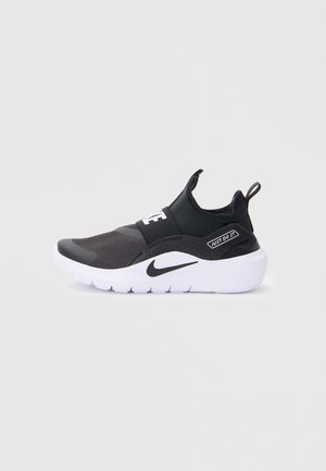 Baskets de sport noires avec une tige texturée, une sangle élastique et une semelle blanche. Présente le logo "JUST DO IT" et un design épuré.