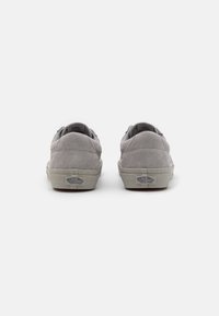Graue Wildleder-Sneaker zeichnen sich durch ein niedriges Profil mit einer strukturierten Oberfläche, kontrastierenden hellen Gummisohlen und dezentem Branding an der Ferse aus.
