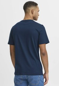 Tamnoplava pamučna majica s kratkim rukavima i okruglim izrezom, s glatkom teksturom i jednostavnim, neukrašenim dizajnom na leđima.