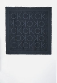 Sciarpa nera realizzata in morbido tessuto, caratterizzata da un motivo a logo CK tono su tono su tutta la superficie e bordi frangiati per un tocco di texture in più.