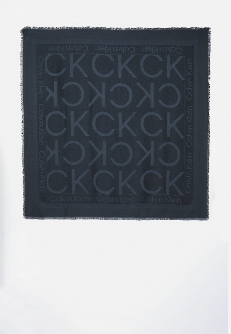 Sciarpa nera realizzata in morbido tessuto, caratterizzata da un motivo a logo CK tono su tono su tutta la superficie e bordi frangiati per un tocco di texture in più.