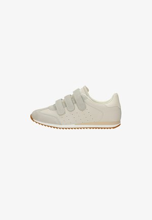 Sneaker beige chiaro con tre strisce in velcro, pannello laterale traforato, punta in suede e suola in gomma marrone.