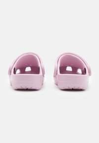 Rosa slip-on träskor med slät yta, öppen häl och ventilationshål. Har en slitstark gummisula med mönstrat mönster för bra grepp.