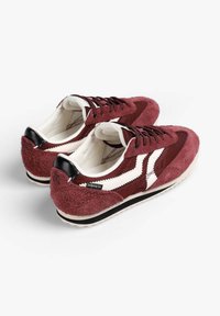 Zapatillas de ante burdeos con rayas blancas y detalles en negro. Material texturizado, punta redonda y cierre con cordones. Forro interior blanco y suela negra.