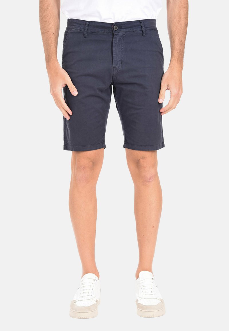 Shorts in cotone blu navy con tasche anteriori, chiusura a bottone e design semplice, abbinati a sneakers bianche.