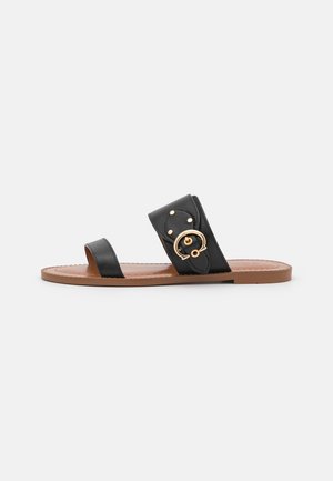 Sort flad slidesandal med to stropper, den ene tynd ved tæerne og den anden bred med guldlås og nitter over foden, brun sål.
