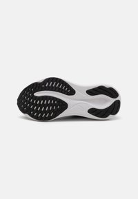 Shoe sole in black and white, featuring a textured rubber pattern for grip, with a curved design and central grooves for flexibility.