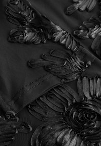 Zwarte stof met ingewikkelde verhoogde bloemenborduursels, met gedetailleerde bloemblaadjes en naadwerk in close-up.