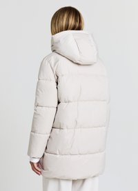 Hellbeige Pufferjacke mit einem durchgehenden Reißverschluss und Kapuze, die ein gestepptes Design mit horizontalen Abschnitten und einer glatten, glänzenden Textur aufweist.