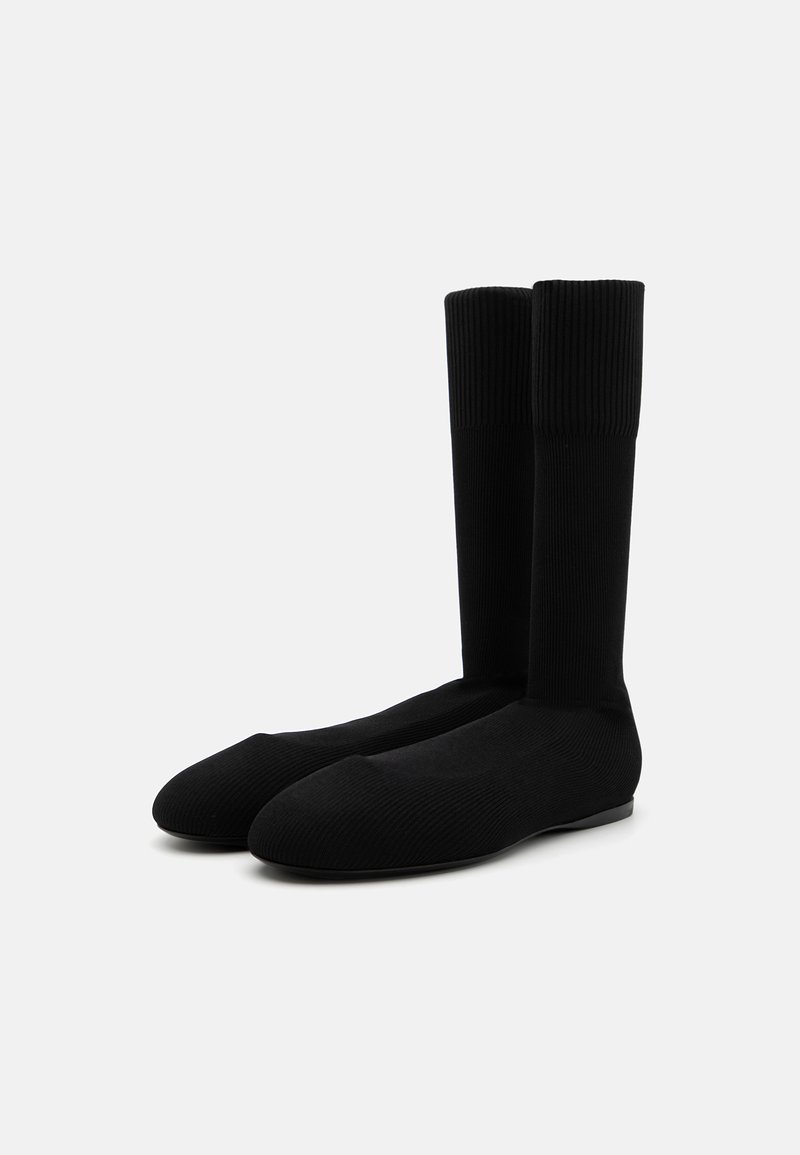 Svarta knälånga strumpor i ribbat material, med sömlös design, slät yta och rundade tår.