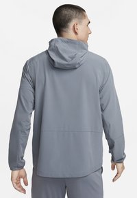 Hall hall kapuutsiga jope, millel on sile tekstuur, elastsed varrukaotsad ja sirge lõige. Omab õmbluse detaile ning esiküljel on kängurum-tasku.