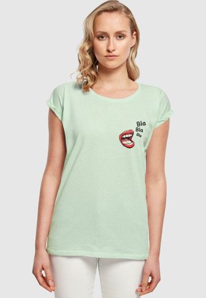 Mintgrünes T-Shirt aus weichem Stoff, mit einem Grafikdesign von roten Lippen und dem Text "Bla Bla Bla" in Schwarz, mit hochgerollten Ärmeln und einem runden Ausschnitt.