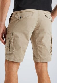 Khaki cargo shorts featuring multiple pockets, button details, and a relaxed fit. Made from lightweight, textured cotton fabric.