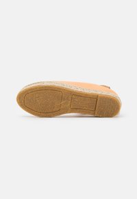 Sapato espadrilha com parte superior em lona laranja clara e palmilha em corda de juta natural. Sola de borracha com superfície texturizada para aderência.