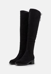 Schwarze kniehohe Stiefel aus Wildleder, mit Blockabsatz, glatter Textur, Nahtdetails und verstellbarem Zugband an der Oberseite.