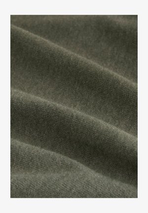 Olivenfarbener Stoff mit einer weichen, strukturierten Oberfläche, die dezente Variationen in Webart und Farbnuance aufweist, angeordnet in einer drapierten, geschichteten Weise.