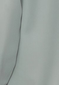 Light blue fabric with a smooth texture, showing fine wrinkles and folds. The material appears soft and drapes gently.