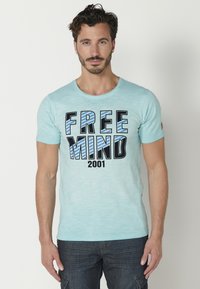 Világoskék, rövid ujjú póló kerek nyakkal. A póló elülső részén merész "FREE MIND 2001" felirat látható fekete és kék színben. Puha, texturált anyag.