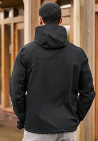 Jachetă impermeabilă neagră cu guler înalt și glugă. Dispune de o textură netedă și un design ajustat. Cusături întărite și mansete elastice.