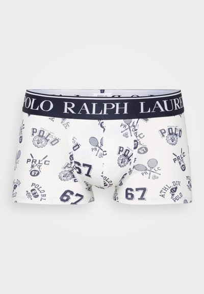 Valkoiset bokserit, joissa on toistuva tummansininen painatus logoista, numeroista ja tennismailoista. Elastinen vyötärö, jossa on "Polo Ralph Lauren" -brändäys.