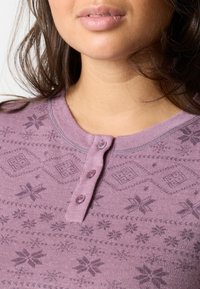 Lichtpaarse langermige top met een henley ontwerp, knoopsluiting aan de voorkant en een gestructureerd patroon van sneeuwvlokken en geometrische vormen. Zachte stof.