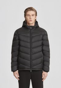 Giacca a puffo nera con cappuccio, caratterizzata da un design trapuntato e una cerniera frontale. Texture liscia, vestibilità slim e polsini elasticizzati.