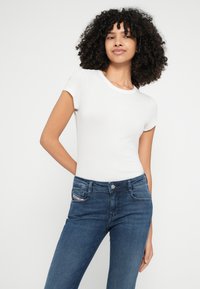 Λευκό ριμπ κοντομάνικο t-shirt συνδυασμένο με σκούρο μπλε τζιν παντελόνι με κλασικό σχέδιο πέντε τσεπών και διακριτικές λεπτομέρειες ραφής.