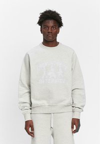Graues Sweatshirt mit Rundhalsausschnitt, gerippten Bündchen und Saum. Hat einen verblassten Grafikdruck auf der Vorderseite. Hergestellt aus einem weichen, strukturierten Stoff.