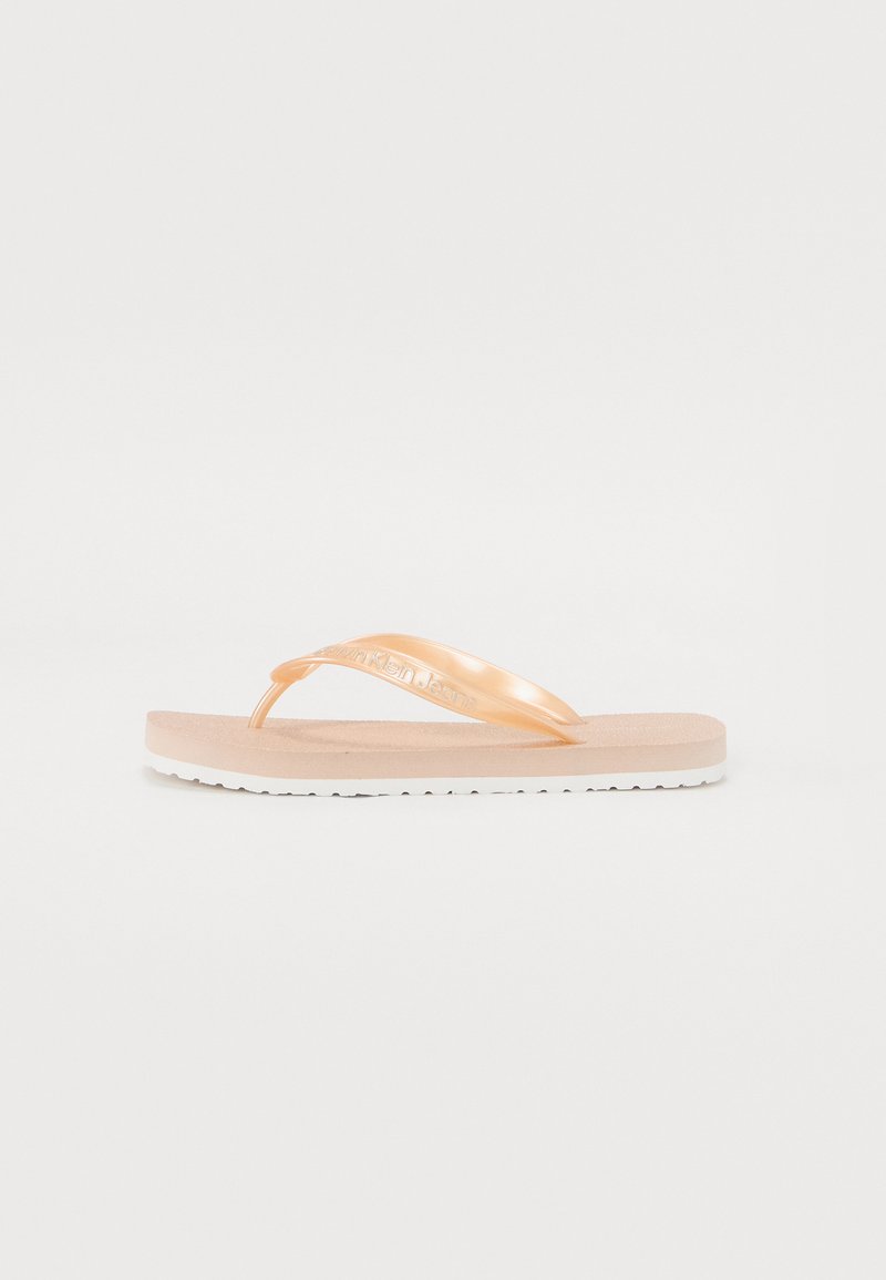 Šviesiai persikiniai šlepetės su blizgiu dirželiu, tekstūruota pado dalimi ir baltais protektoriaus padais. Ant dirželio yra įspaustas prekės ženklo logotipas.