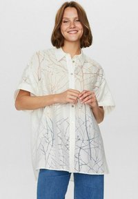 Hvid skjorte med knapper og et let, gennemsigtigt stof med et mønster af grene i bløde pastelfarver. Korte ærmer og afslappet pasform.