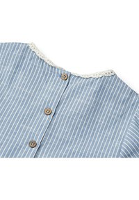 Mėlynos ir baltos juostelės audinys su trimis rudos spalvos mygtukais centre ir balta nėrinių apdaila palei kaklo kraštą.